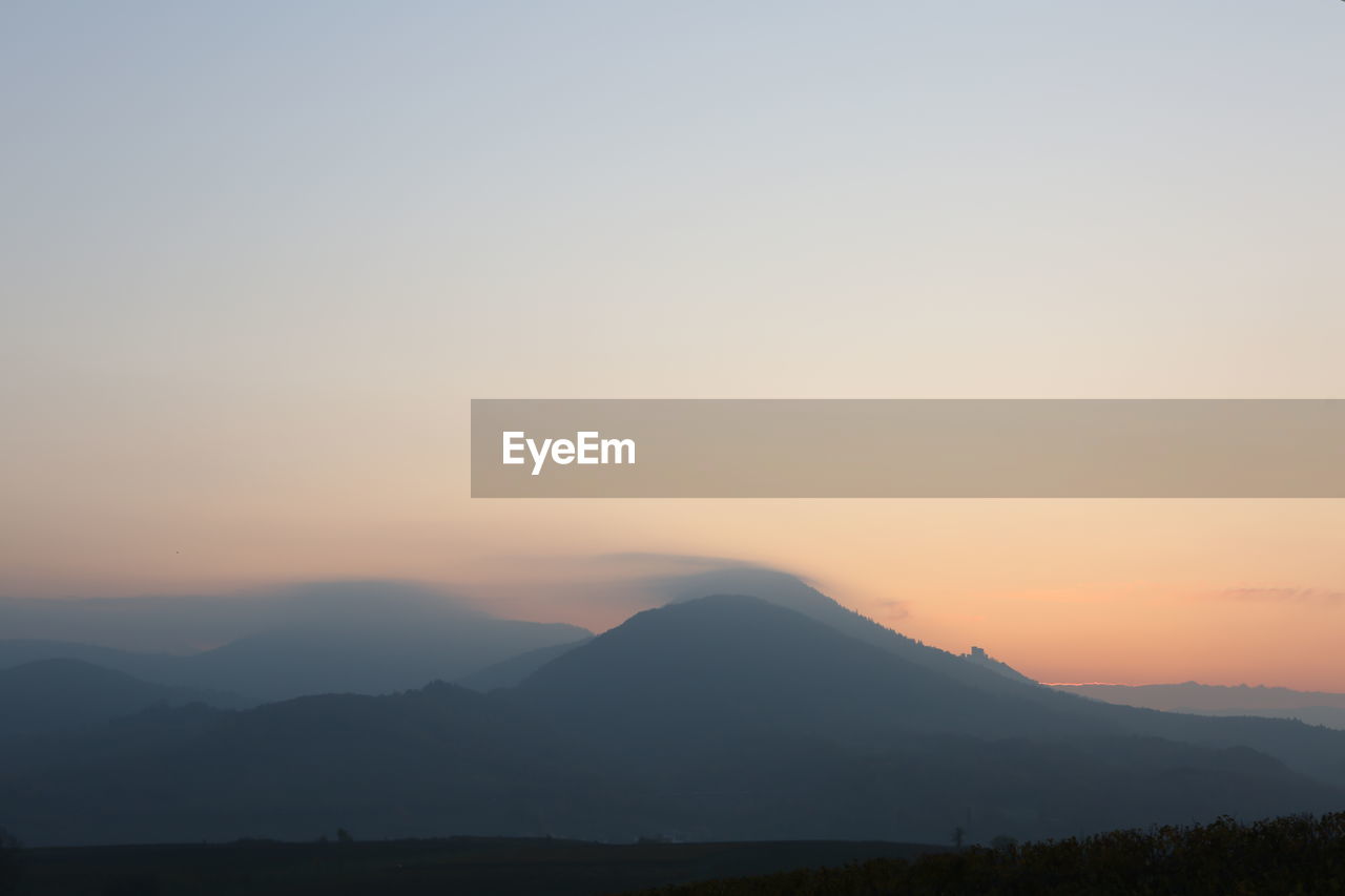 SCENIC VIEW OF SILHOUETTE MOUNTAINS AGAINST CLEAR SKY DURING SUNSET