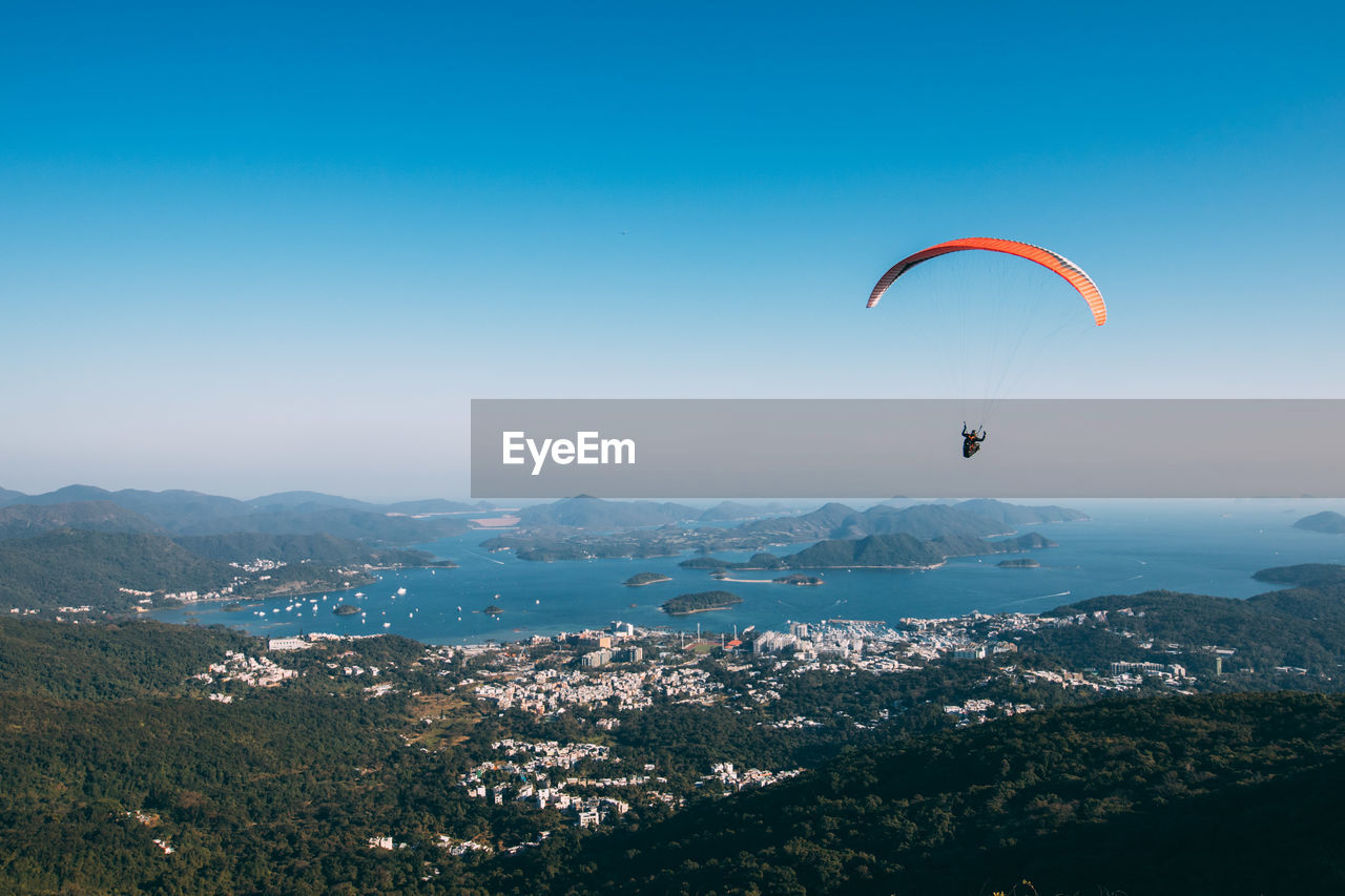 Person paragliding over cityscape against sky