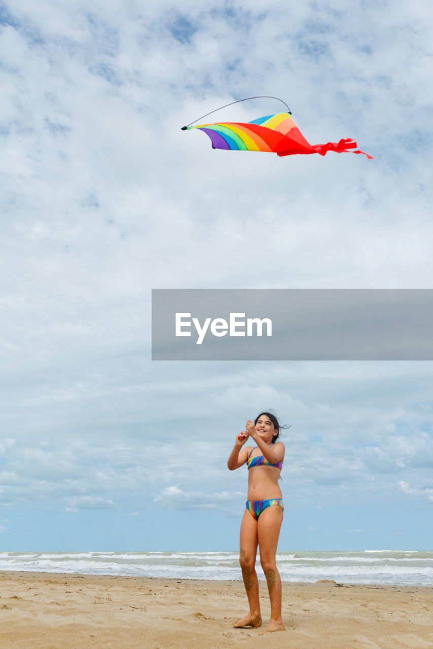 Full length view of a girl flying a kite on the beach