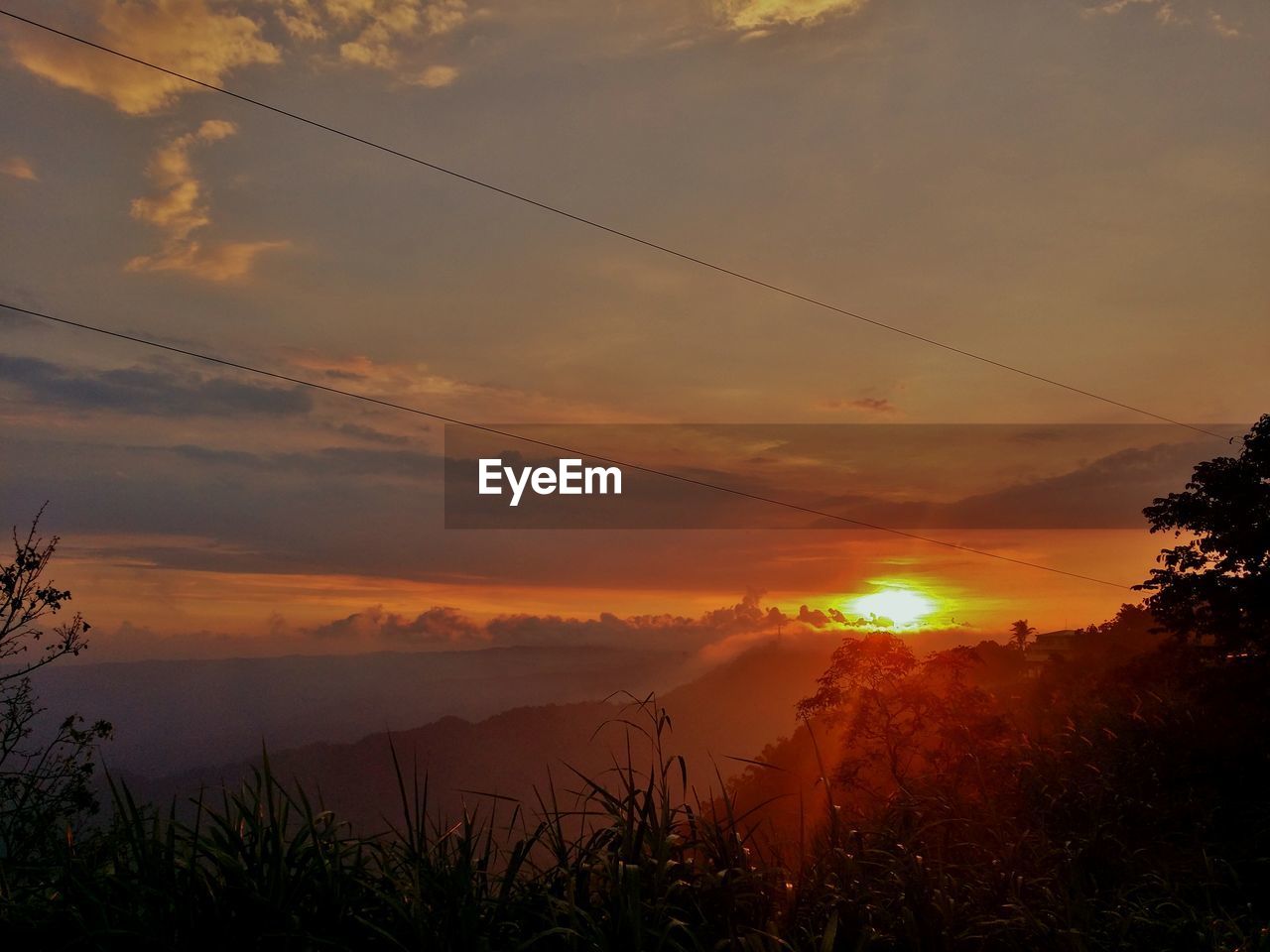 Scenic view of mountains against cloudy sky during sunset