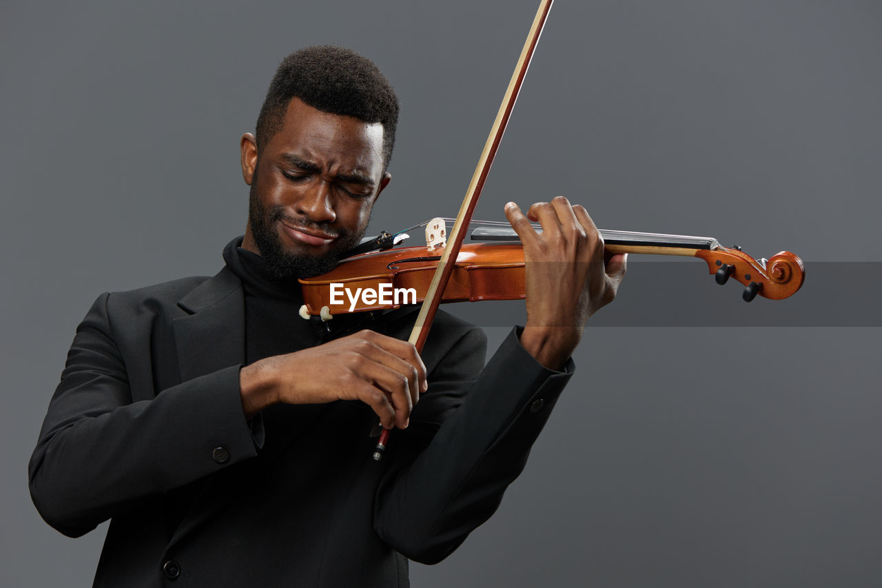 midsection of woman playing violin against white background