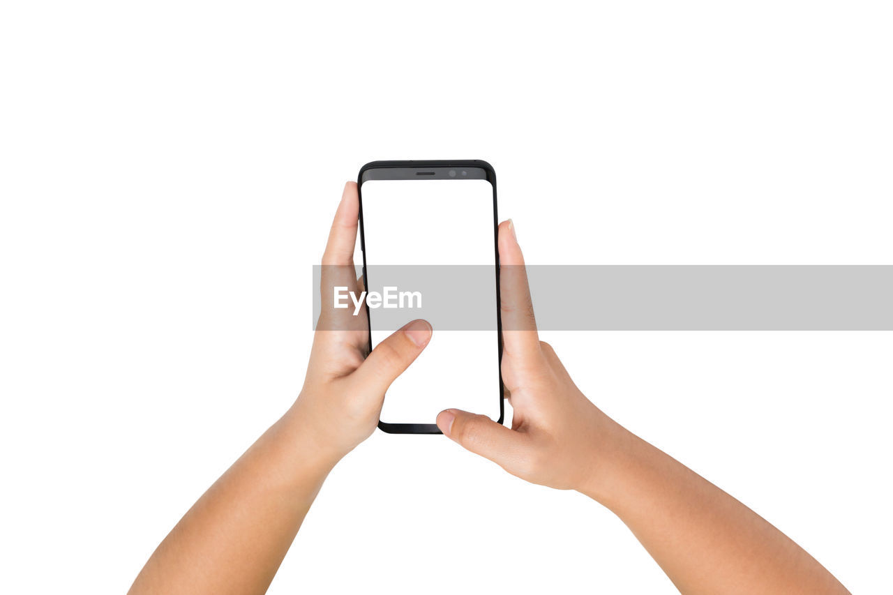 Cropped hands of woman using mobile phone against white background