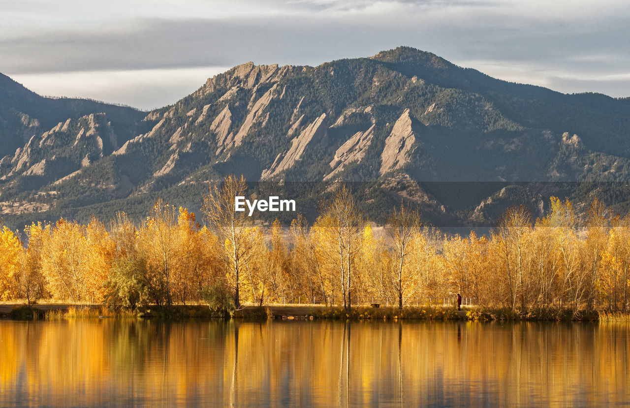 Autumn trees by lake against mountains