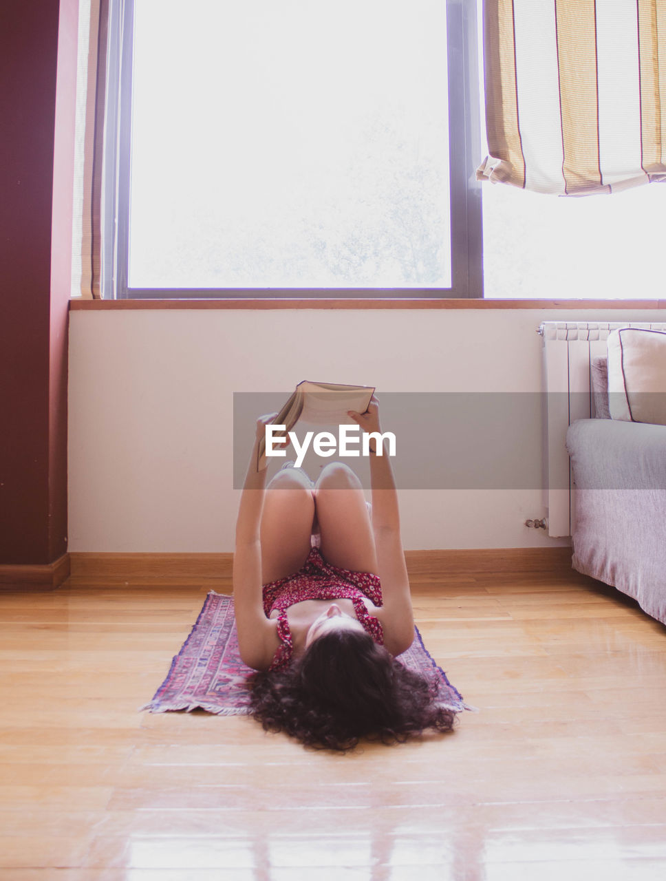 Young girl reading lying on a carpet with her feet up