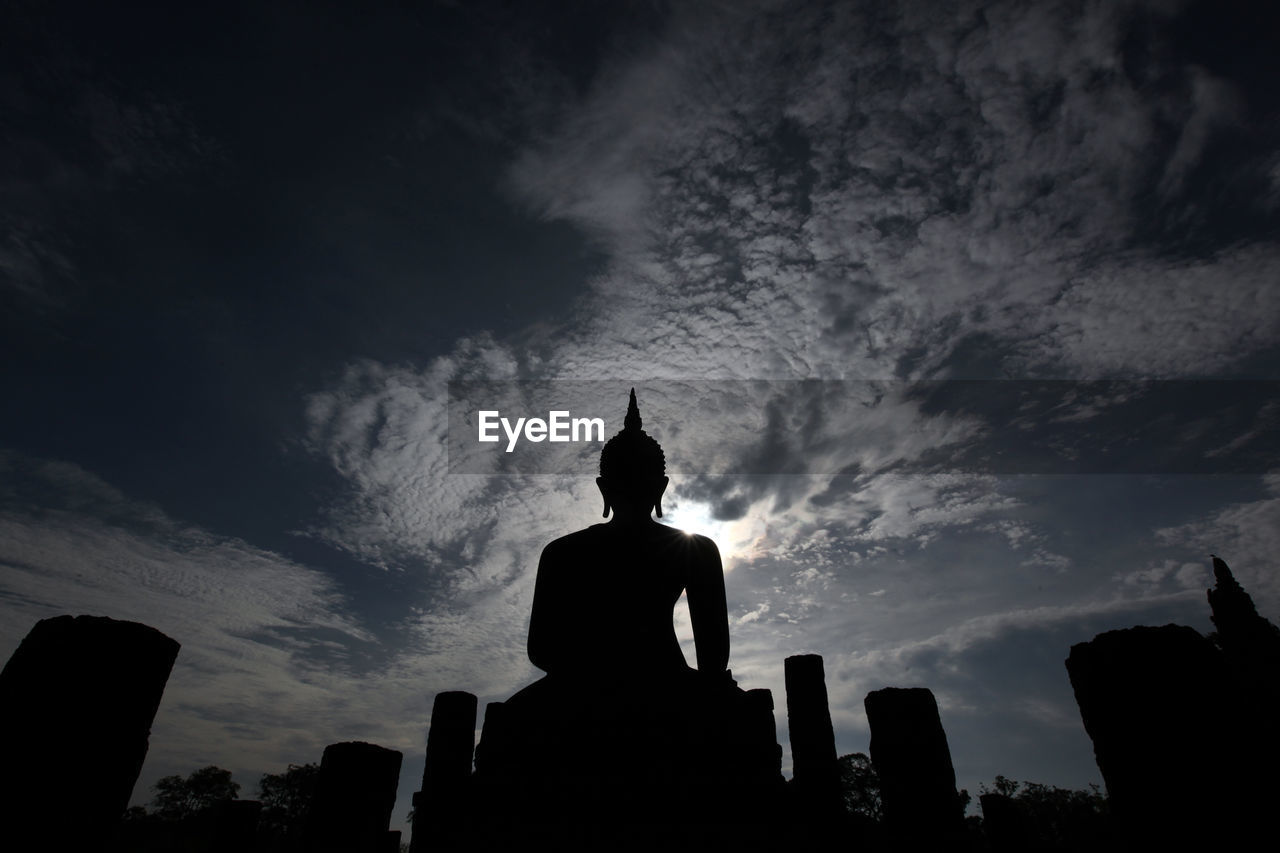 Low angle view of silhouette buddha statue at wat muang against sky