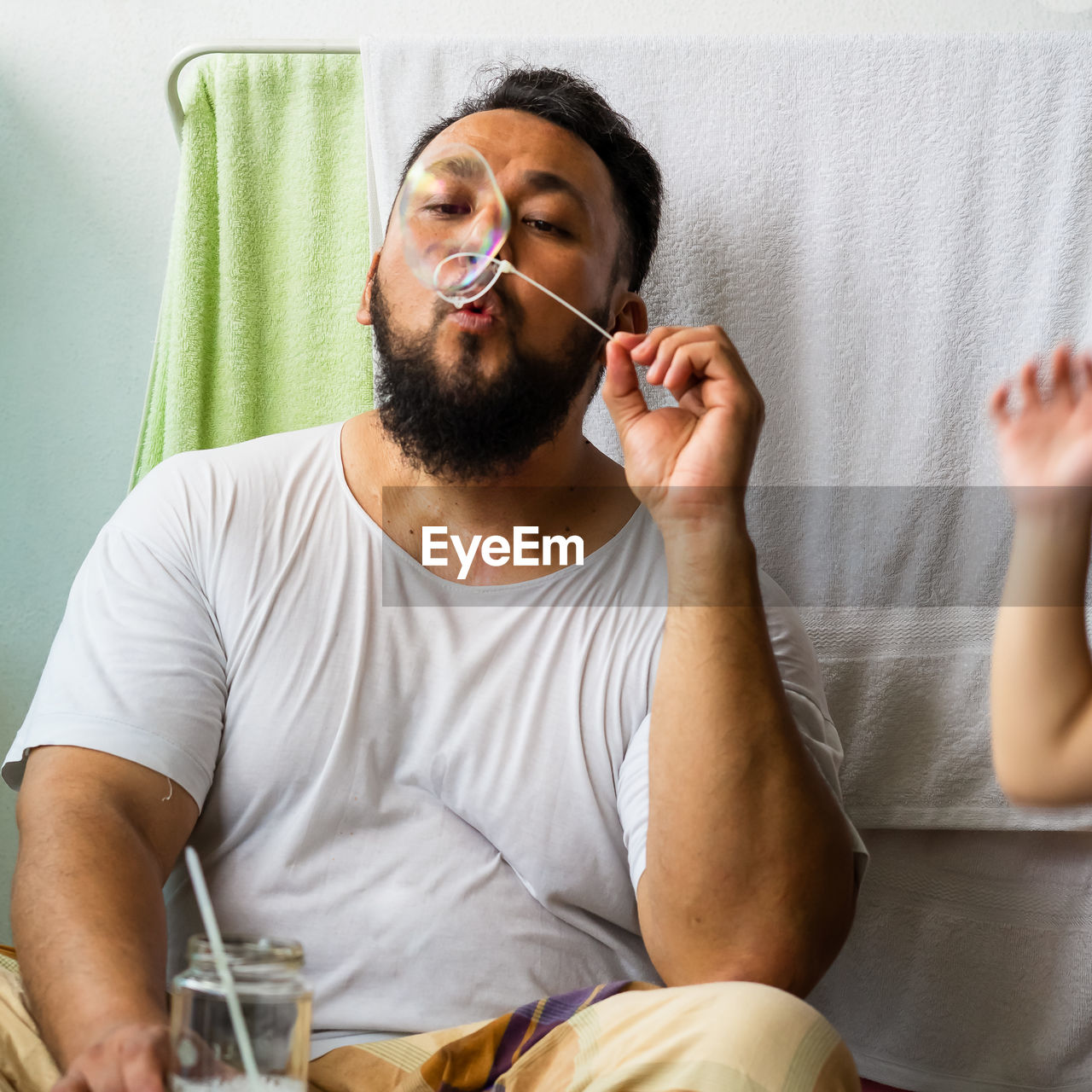 Man blowing bubble while playing with daughter