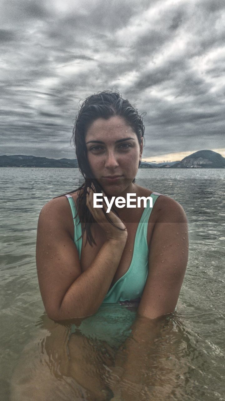 PORTRAIT OF YOUNG WOMAN SWIMMING IN SEA AGAINST SKY