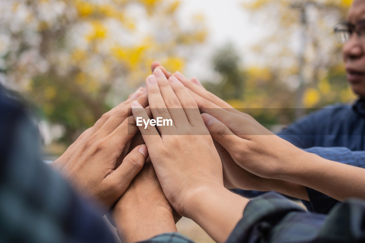 Cropped hand of people stacking hand outdoors