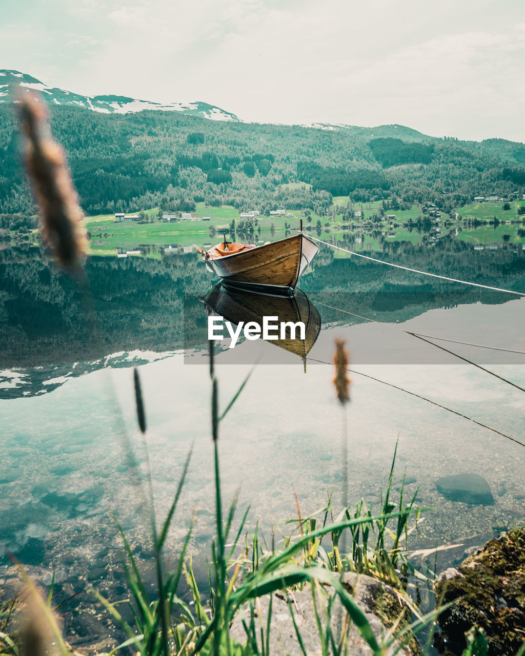 BOAT MOORED BY LAKE AGAINST SKY