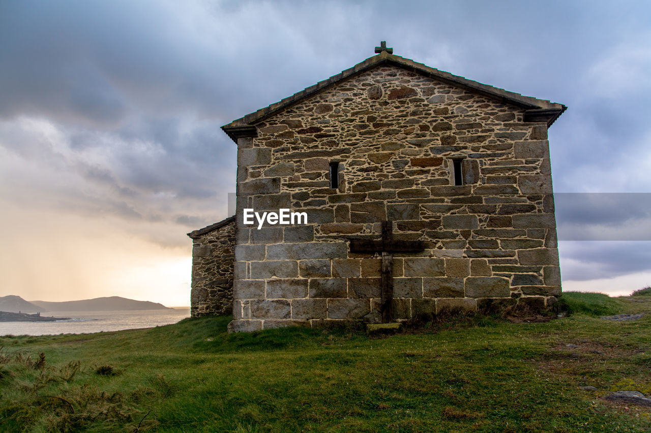 Chapel at coastline against clouds