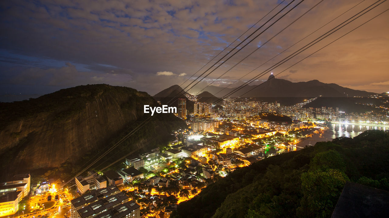 HIGH ANGLE VIEW OF ILLUMINATED CITY BUILDINGS AT NIGHT