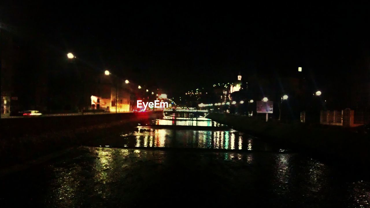 VIEW OF ILLUMINATED STREET LIGHTS IN RIVER AT NIGHT
