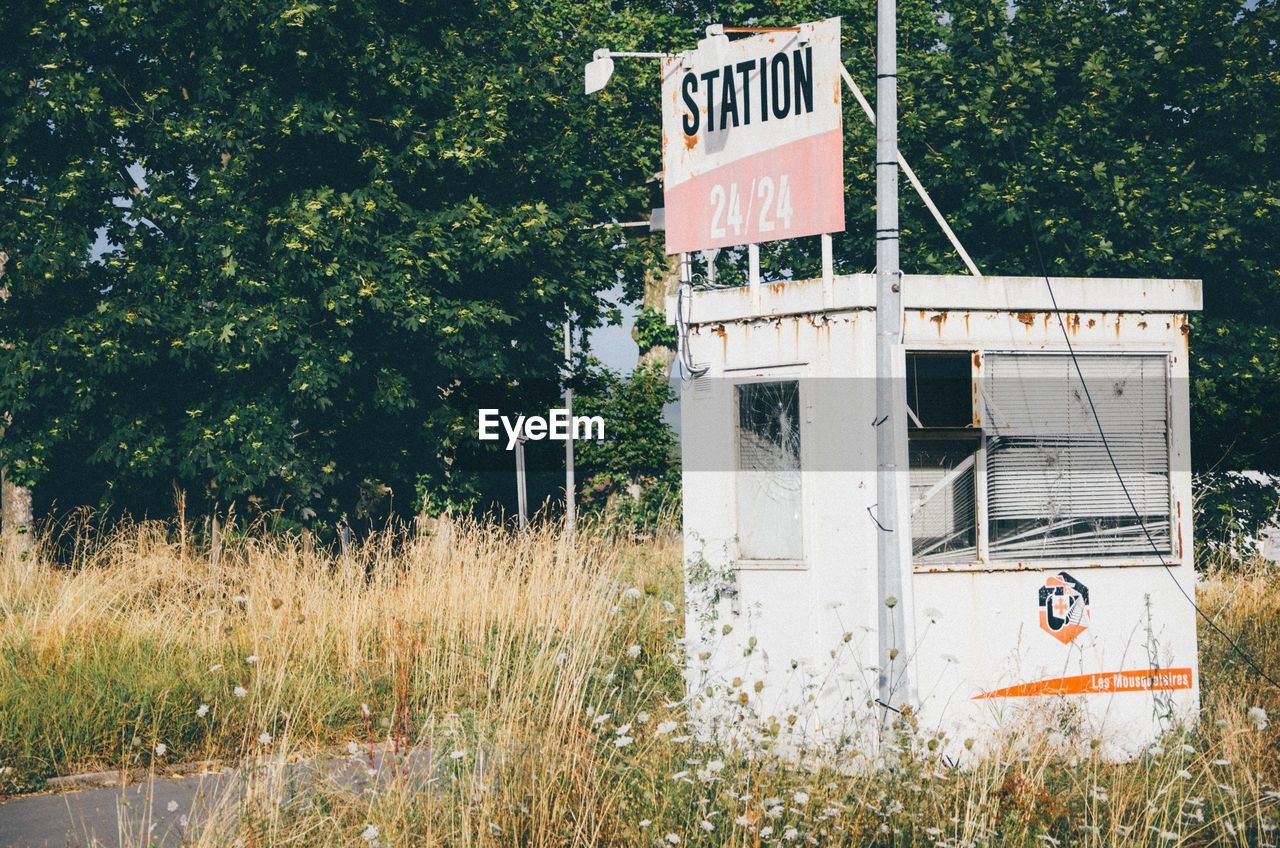 Text on old sign board at fuel pump against trees