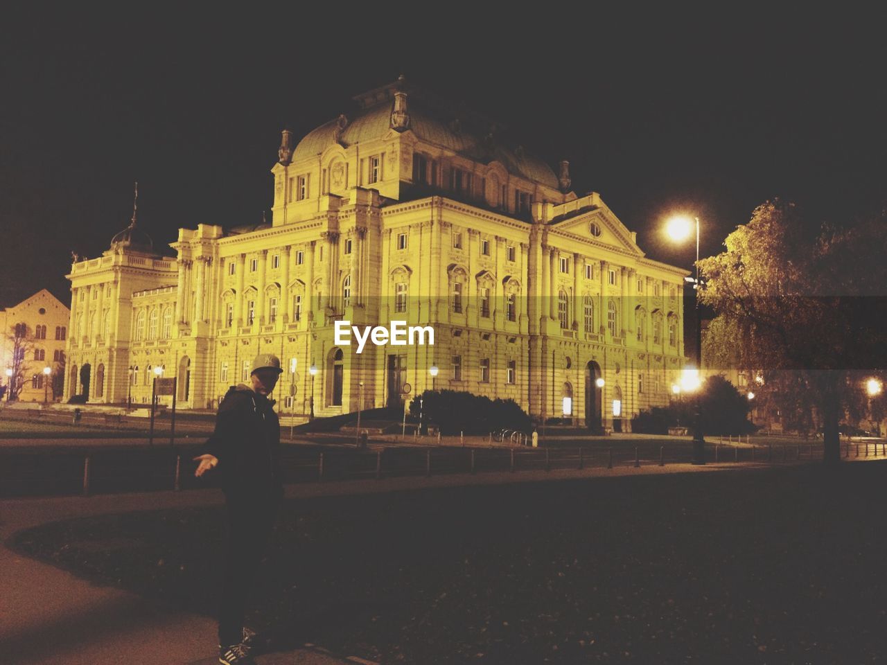 Man standing by illuminated croatian national theatre in zagreb against clear sky at night