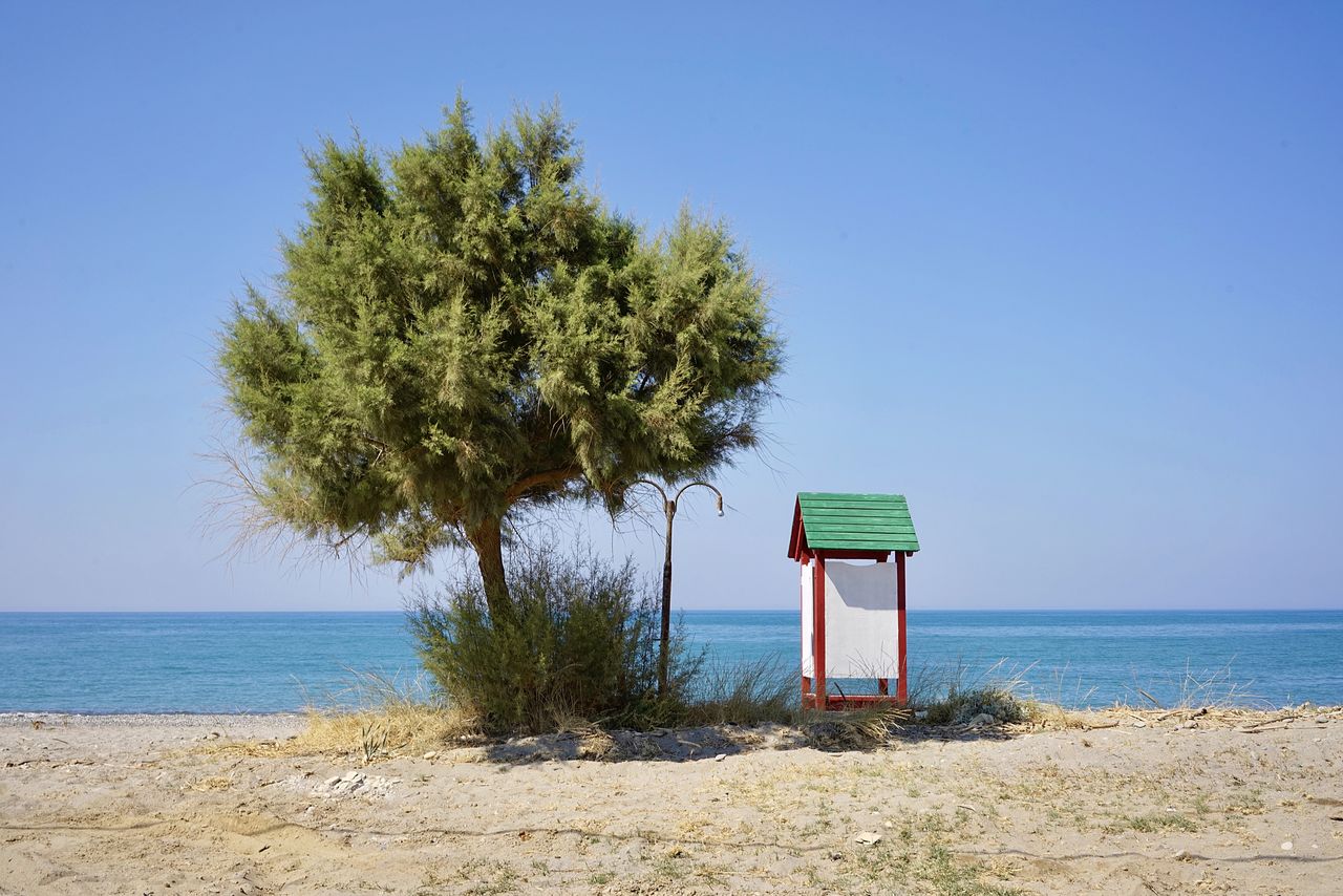 LIFEGUARD HUT ON BEACH AGAINST BLUE SKY