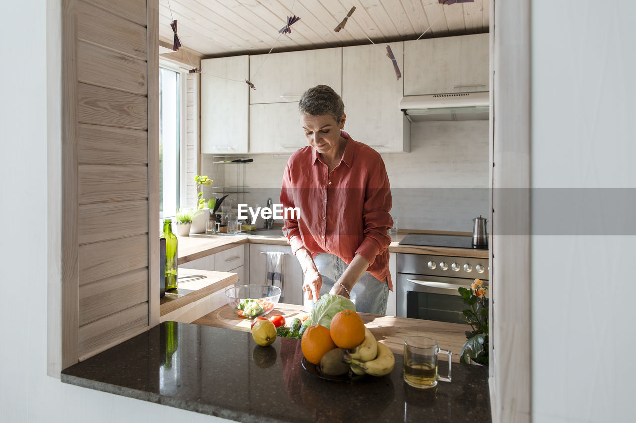 Woman preparing salad in kitchen at home