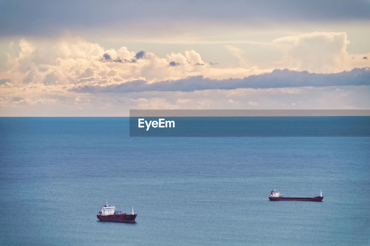 Scenic view of sea and container ships against sky