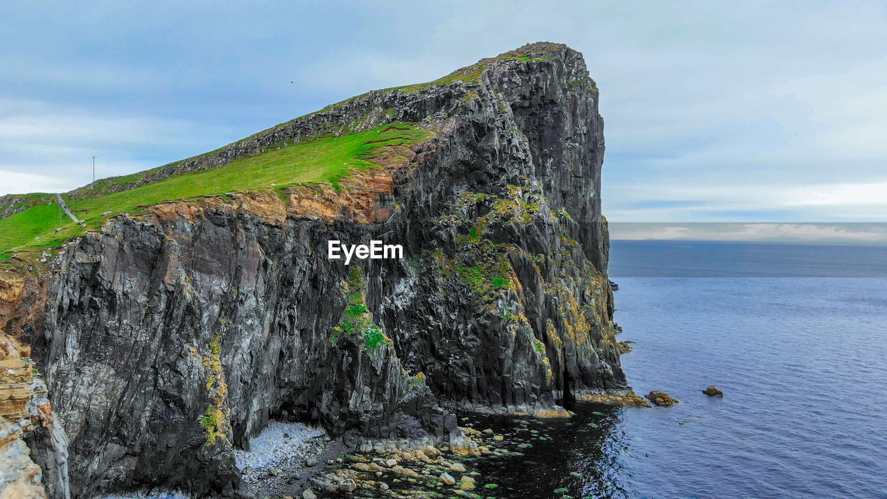 ROCK FORMATION ON SEA AGAINST SKY