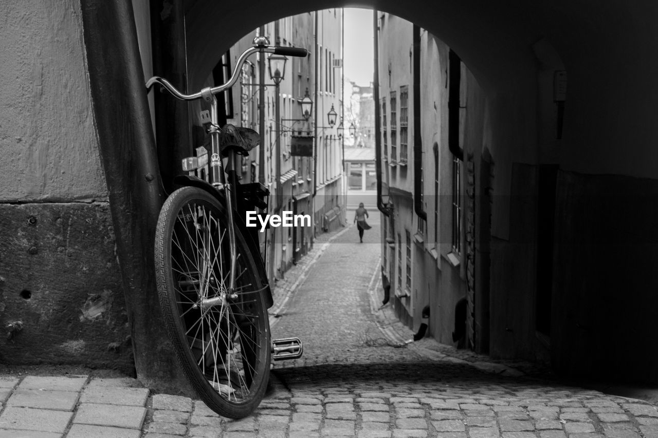 Bicycle parked against alley in city