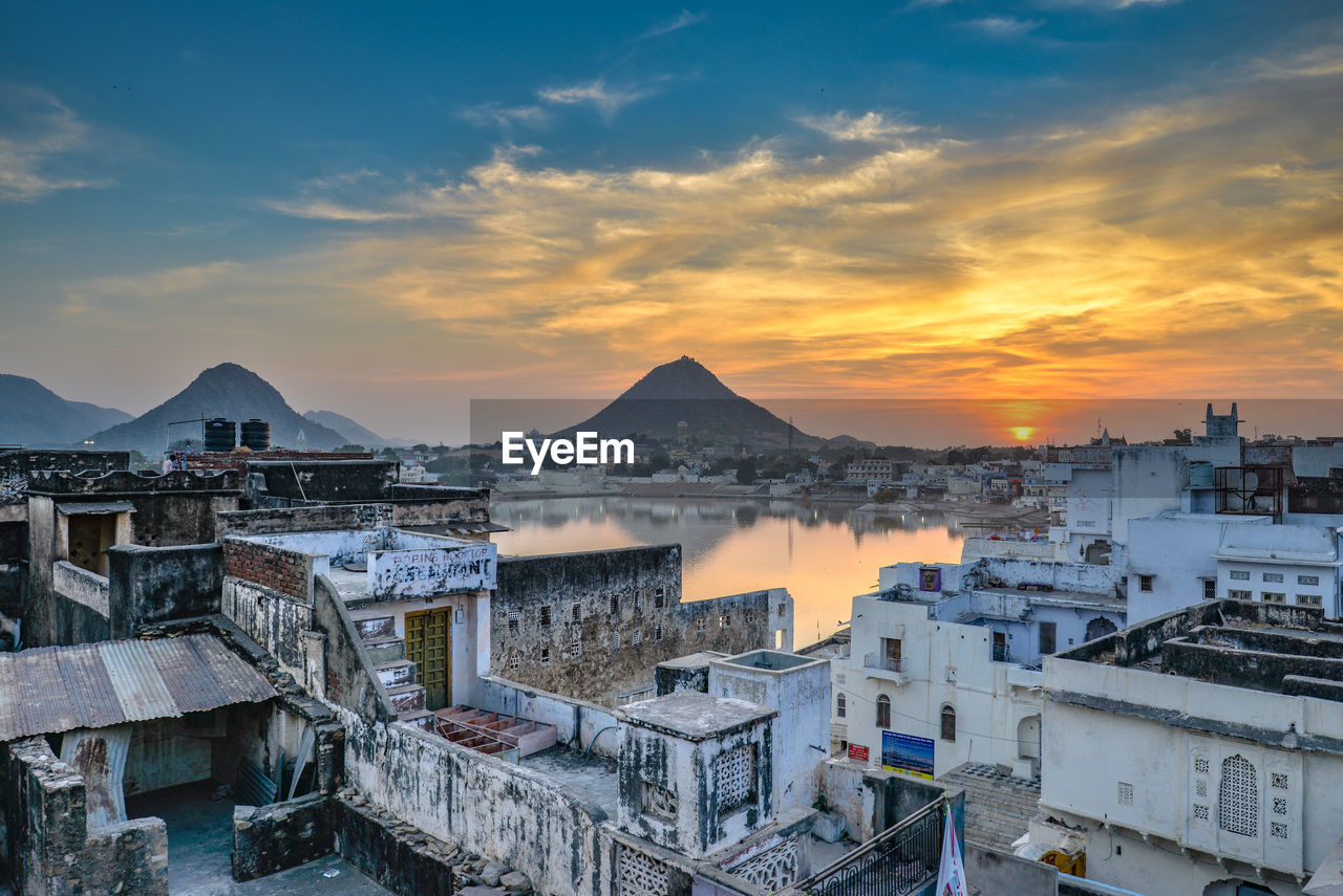 HIGH ANGLE VIEW OF BUILDINGS IN CITY AGAINST SKY DURING SUNSET