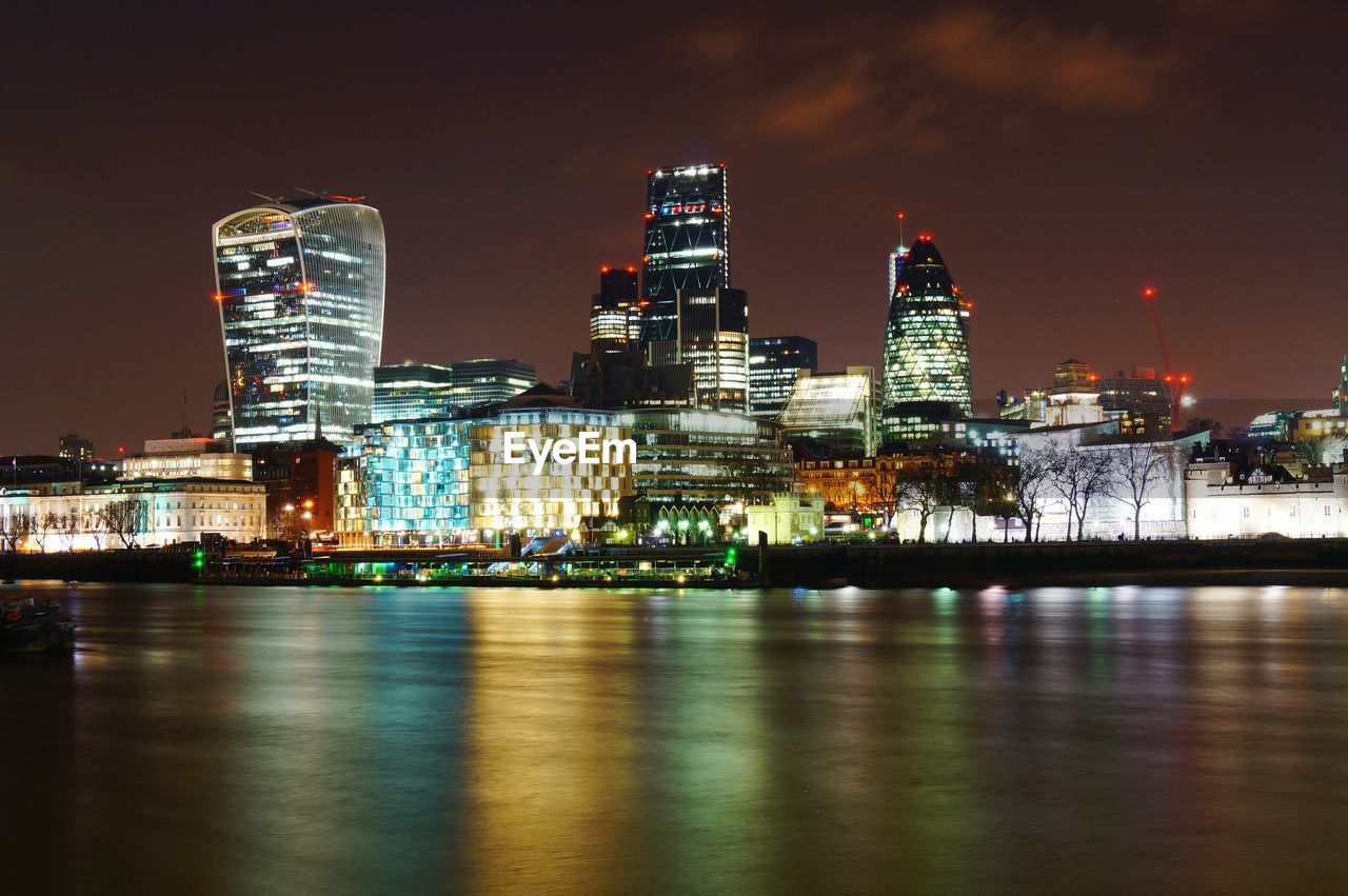 Illuminated downtown district by thames river at night