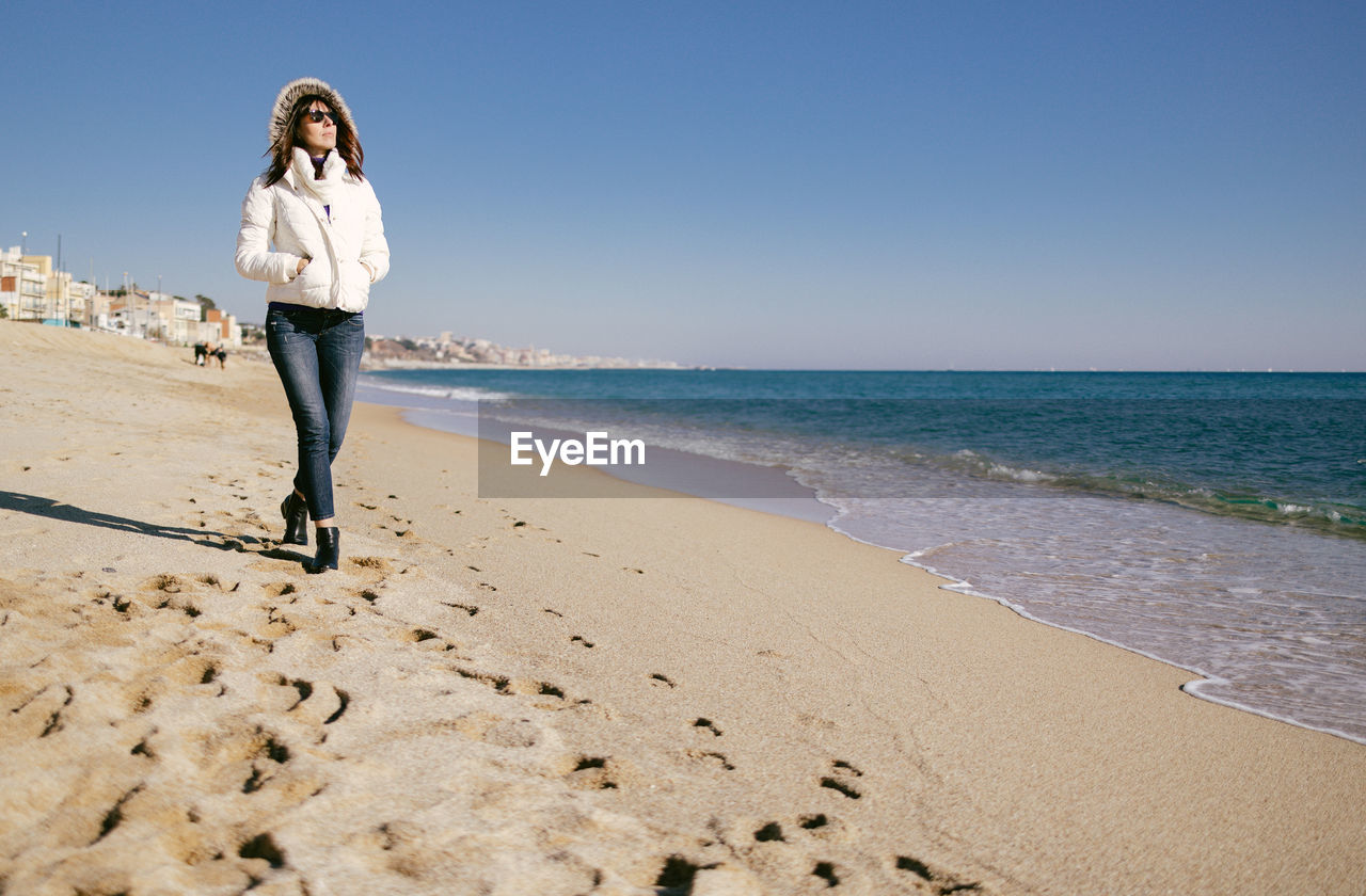 Mature woman walking on the beach on a sunny winter day