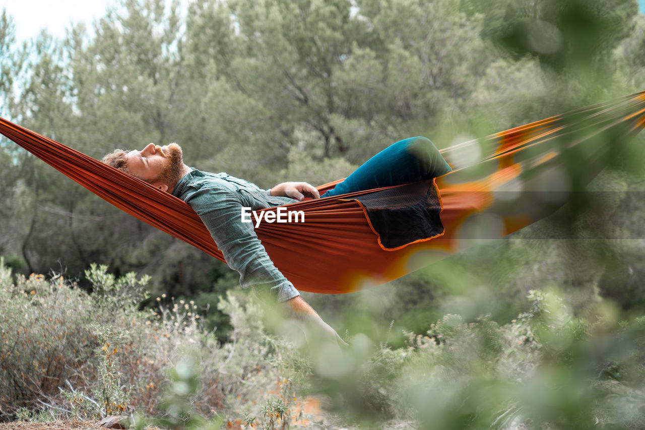 Portrait of man relaxing on hammock in forest