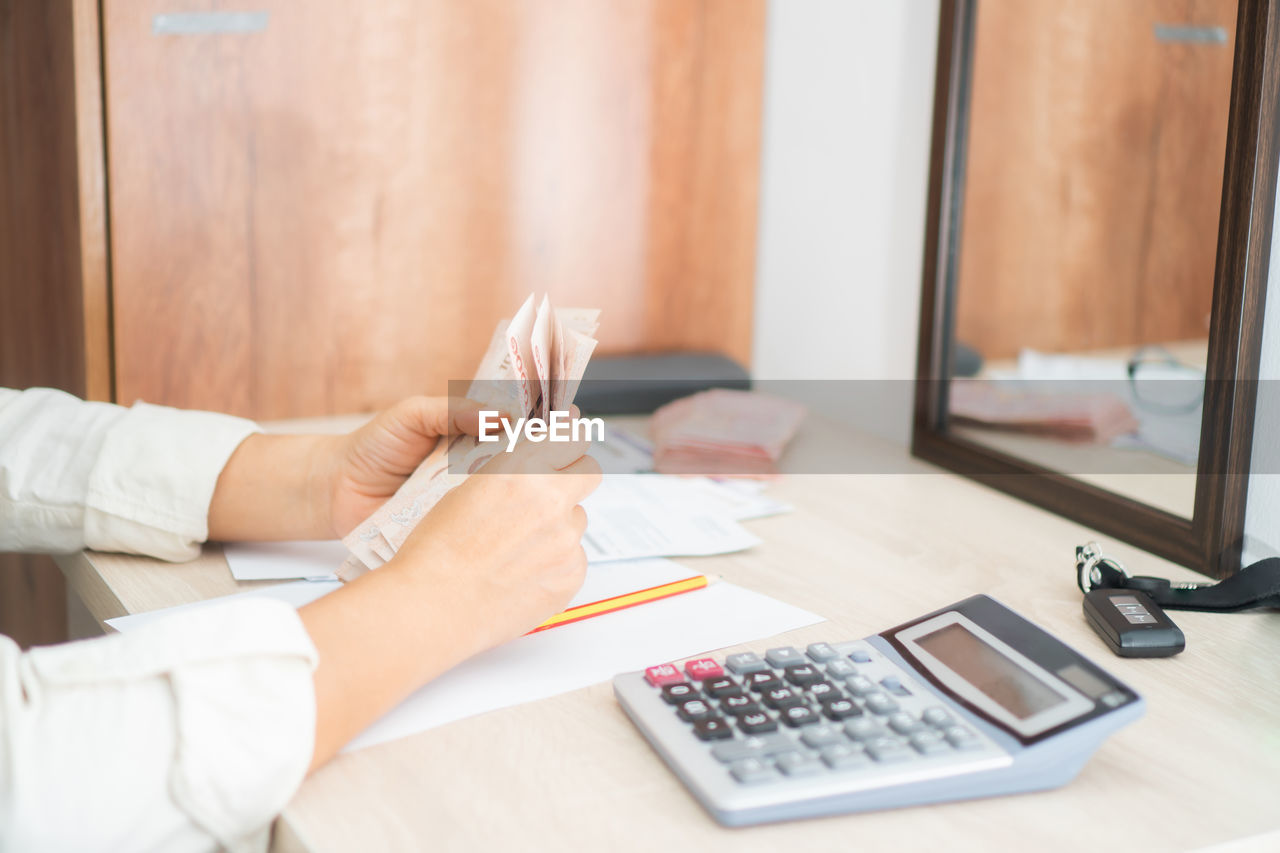 Cropped hands of woman counting paper currency on table