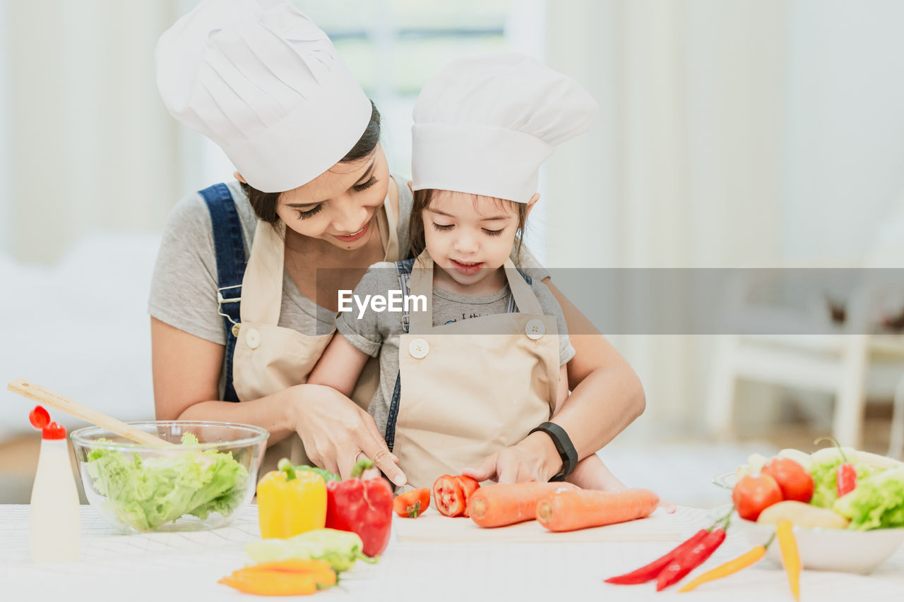 Mother and daughter preparing food on table