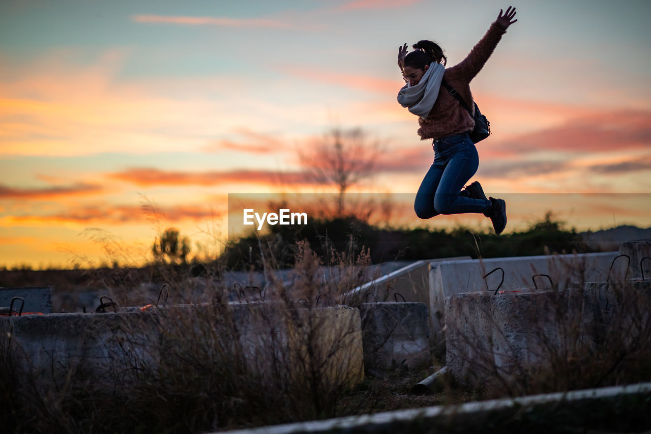 Full length of woman jumping against sky during sunset