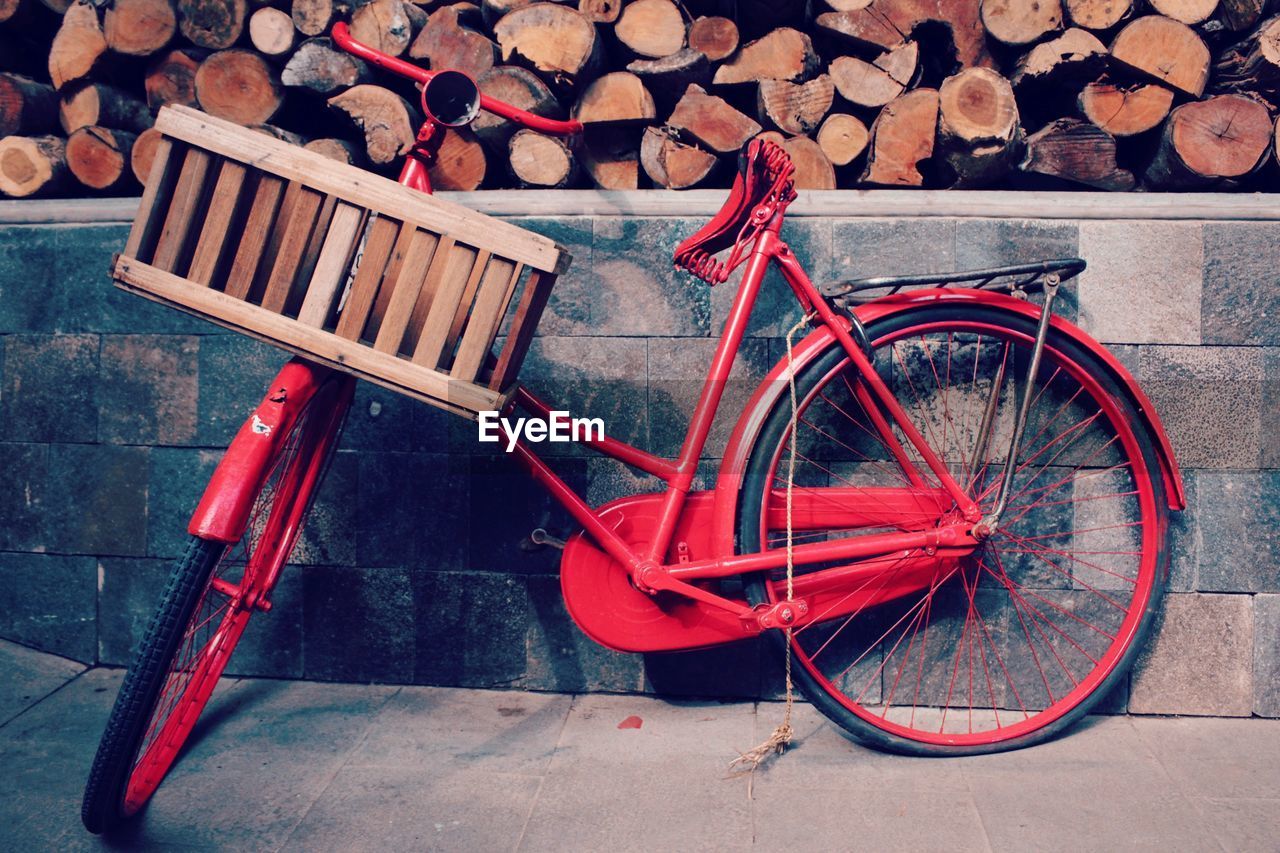 Red bicycle parked on sidewalk against wall