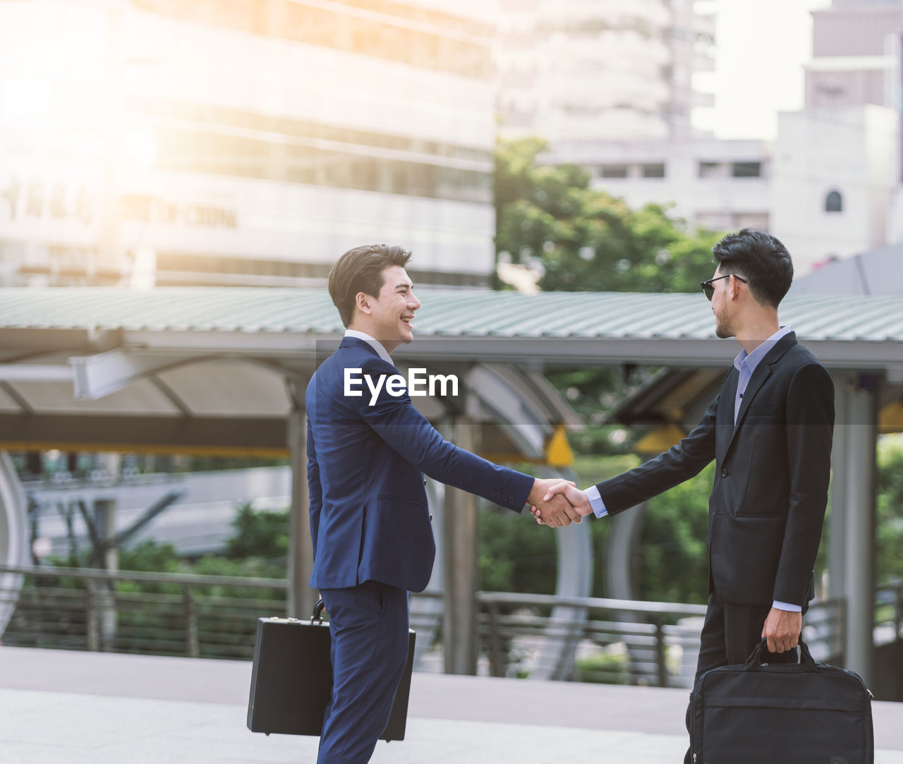 Young businessman shaking hands with colleague in city