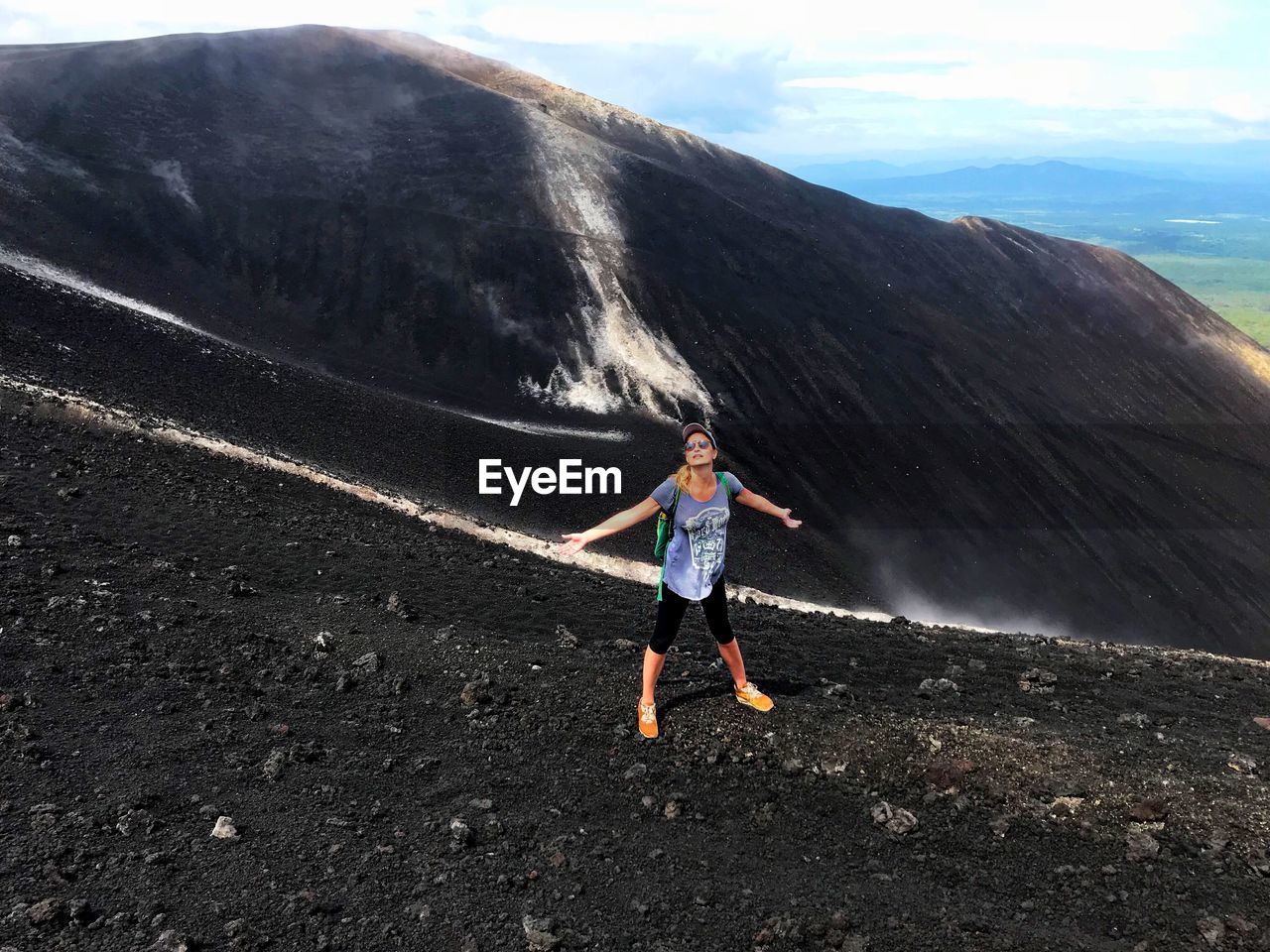 Full length of mature woman with backpack on mountain against sky