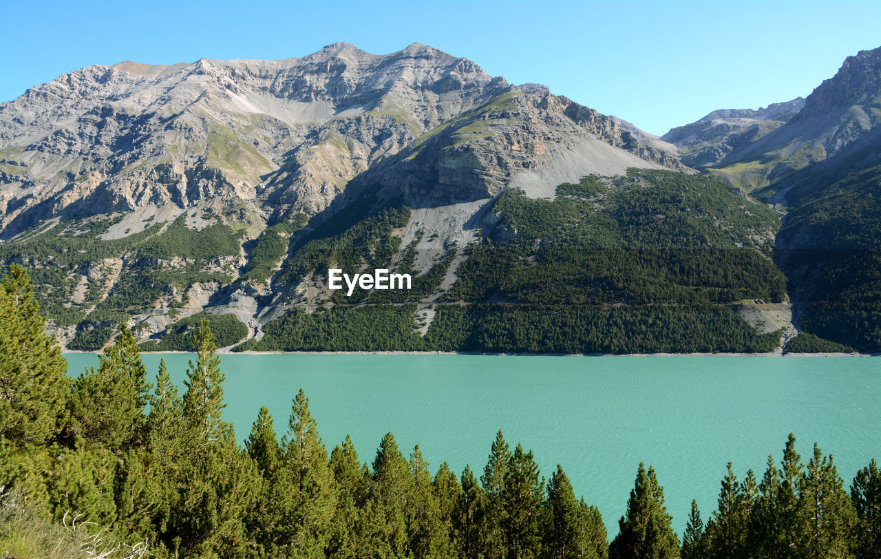 Scenic view of lake and mountains against blue sky