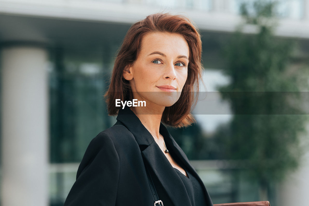 portrait of young woman looking away while standing outdoors