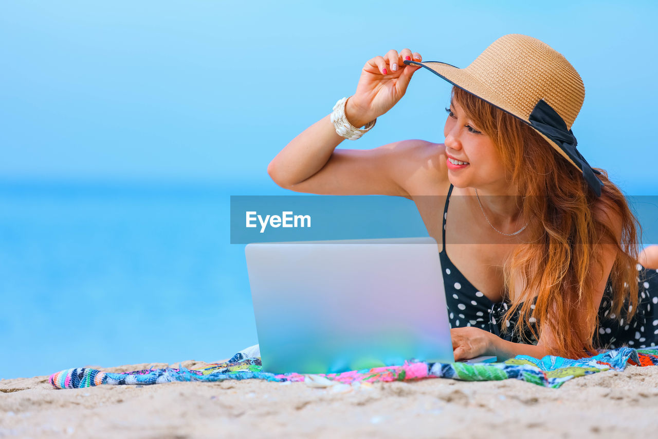 Asian woman working on laptop on the beach, holiday and vacation concept 