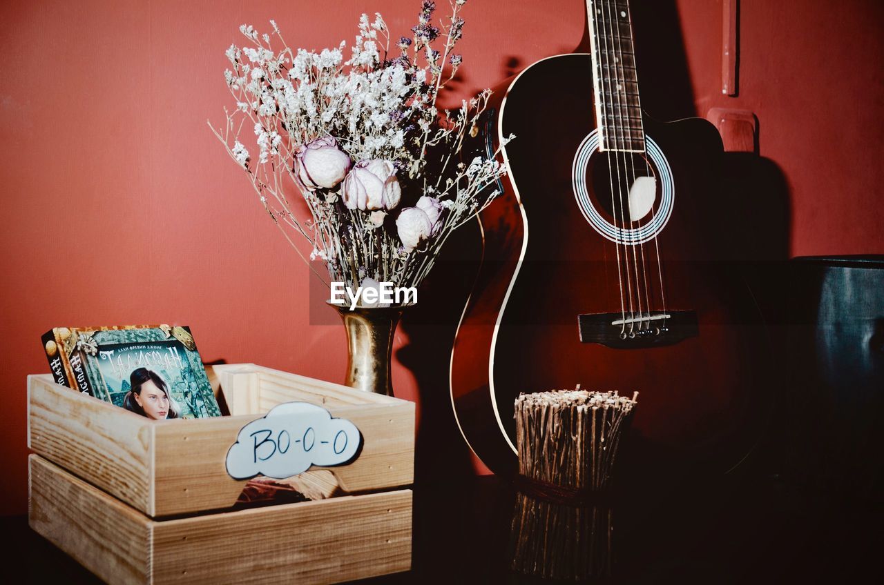 CLOSE-UP OF GUITAR ON TABLE AGAINST WALL