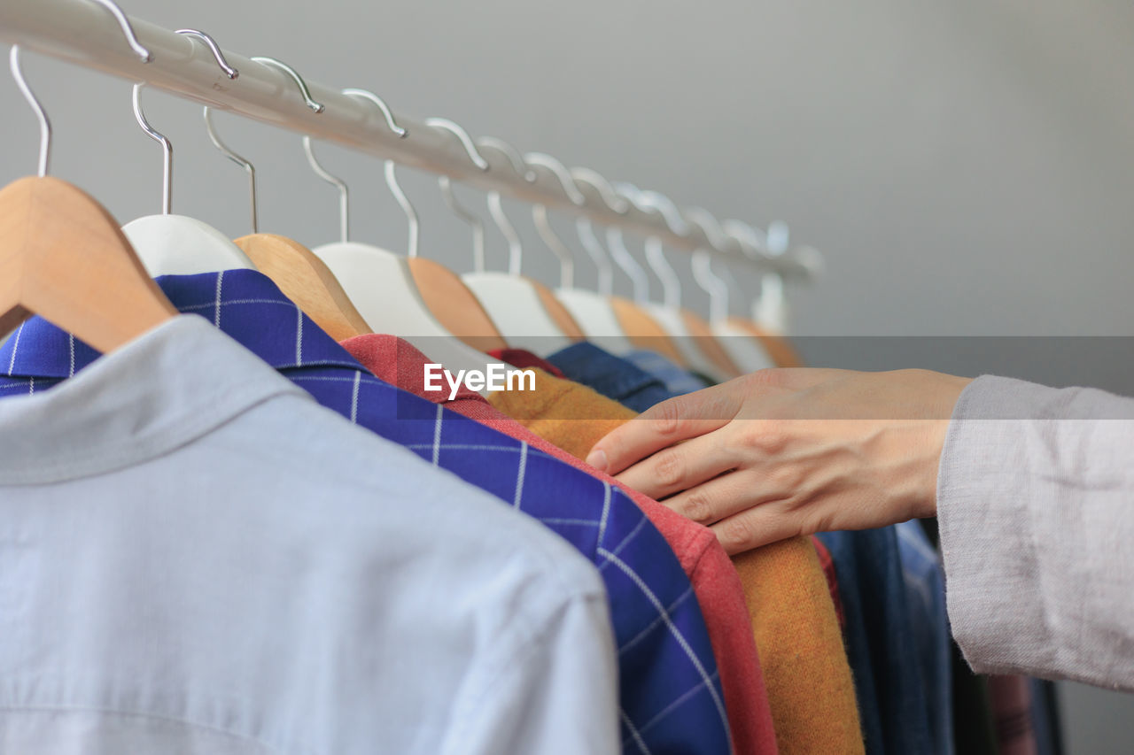 midsection of man with clothes hanging on rack