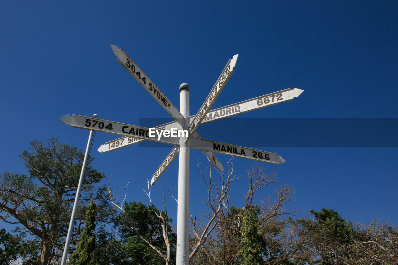 Low angle view of information sign against clear blue sky