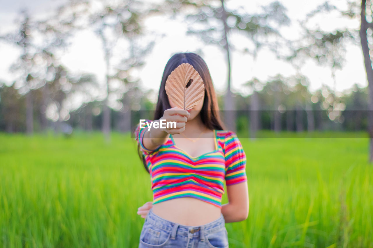 Woman holding leaf while standing on land