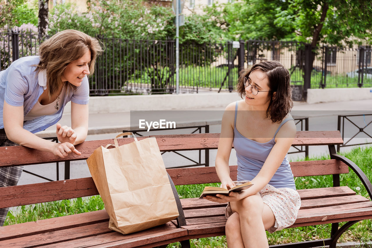 Friends show each other their purchases. communication of girls at social distancing in the park