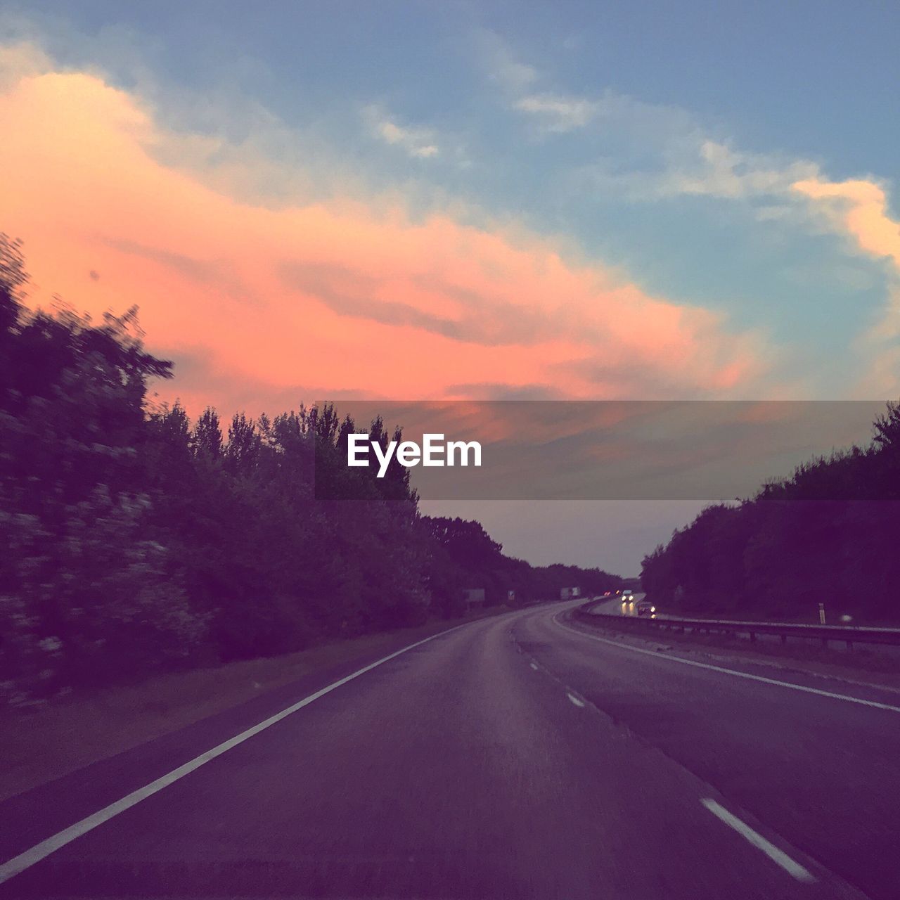 Road amidst trees against sky during sunset