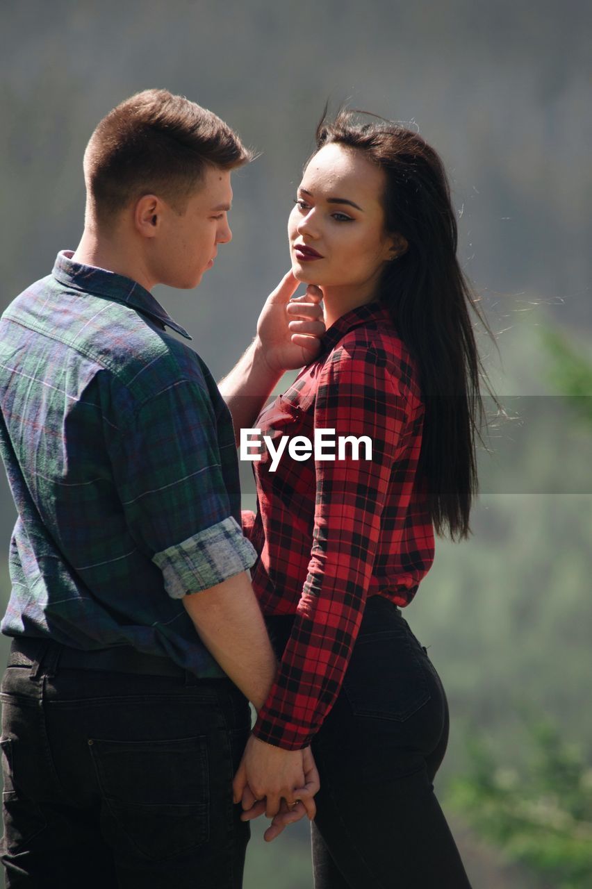 Loving young couple standing in forest