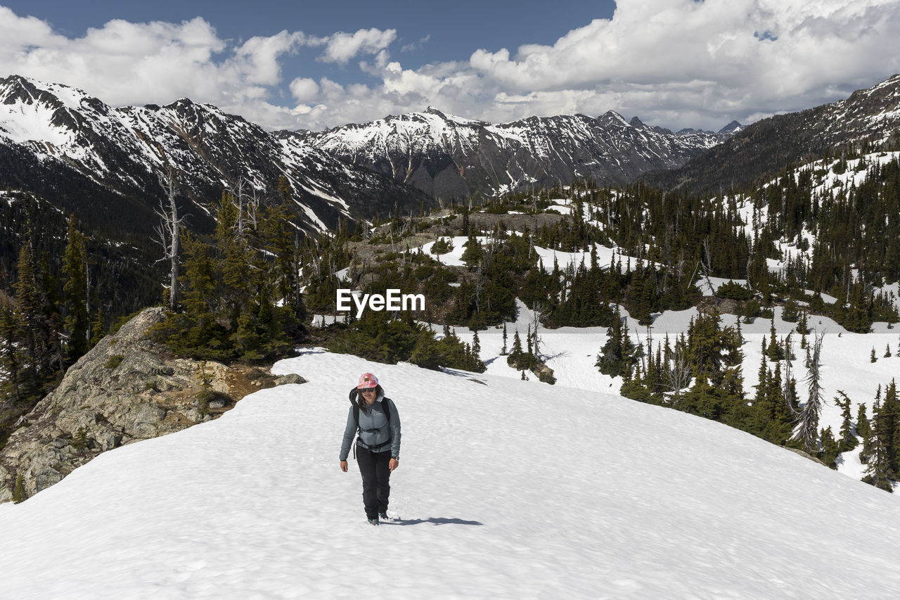 Female hiker walking in snowy mountains on sunny spring day