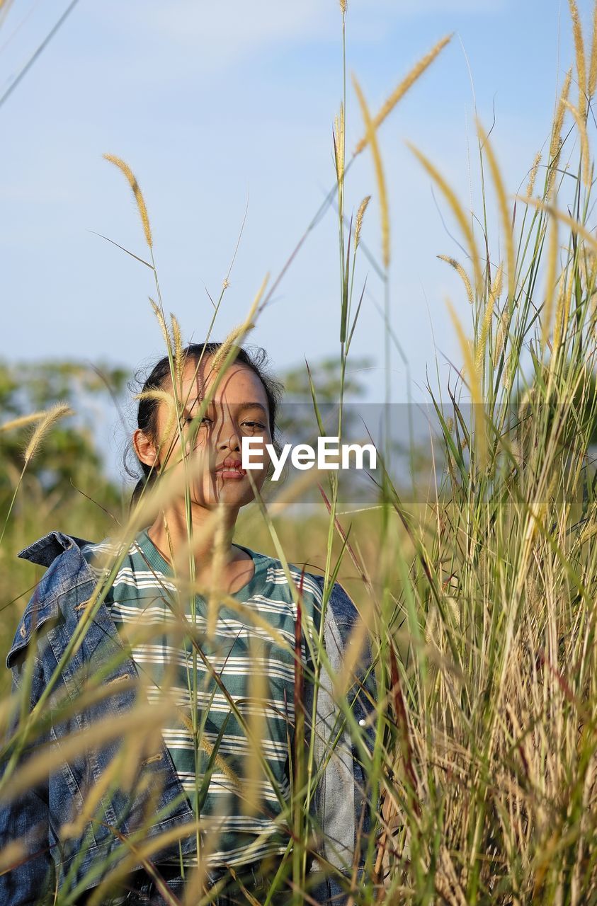 YOUNG WOMAN WEARING MASK ON FIELD AT SUNRISE