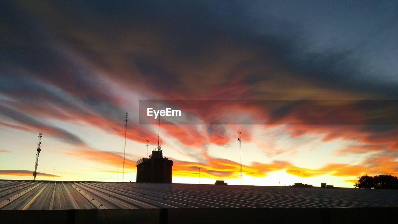 Silhouette houses against sky during sunset