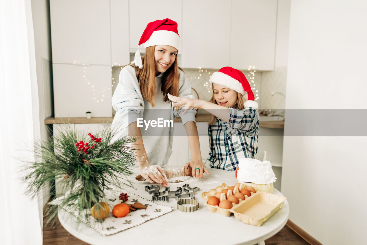 A cute girl helps her older sister prepare a christmas dessert, the girls bake cookies 