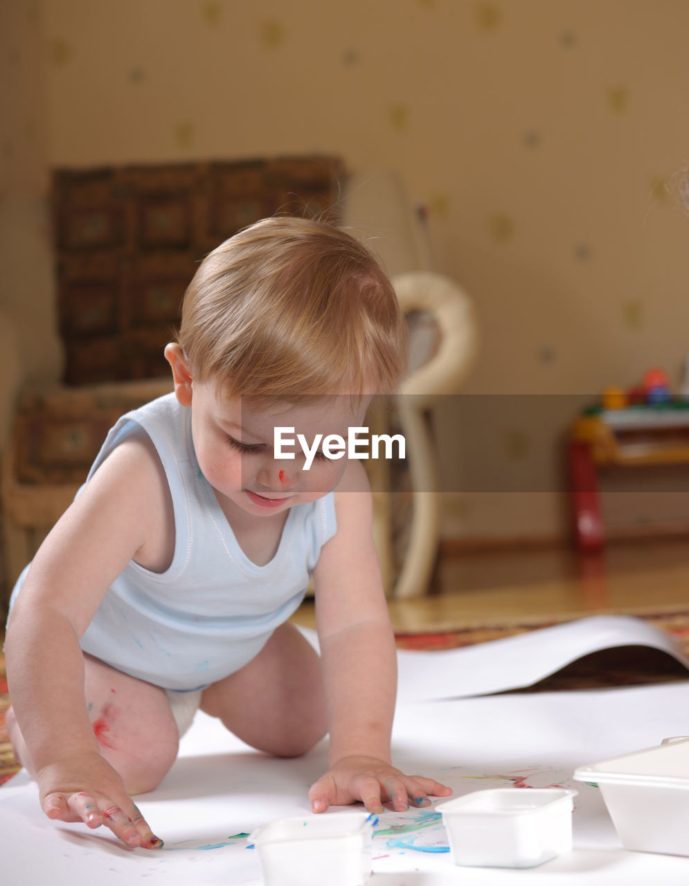 Cute baby boy painting on paper at home