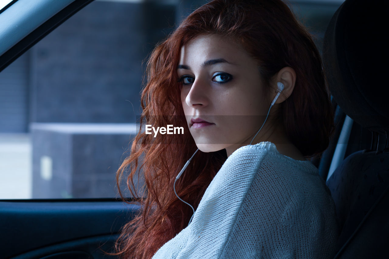 Portrait of beautiful young woman sitting in car