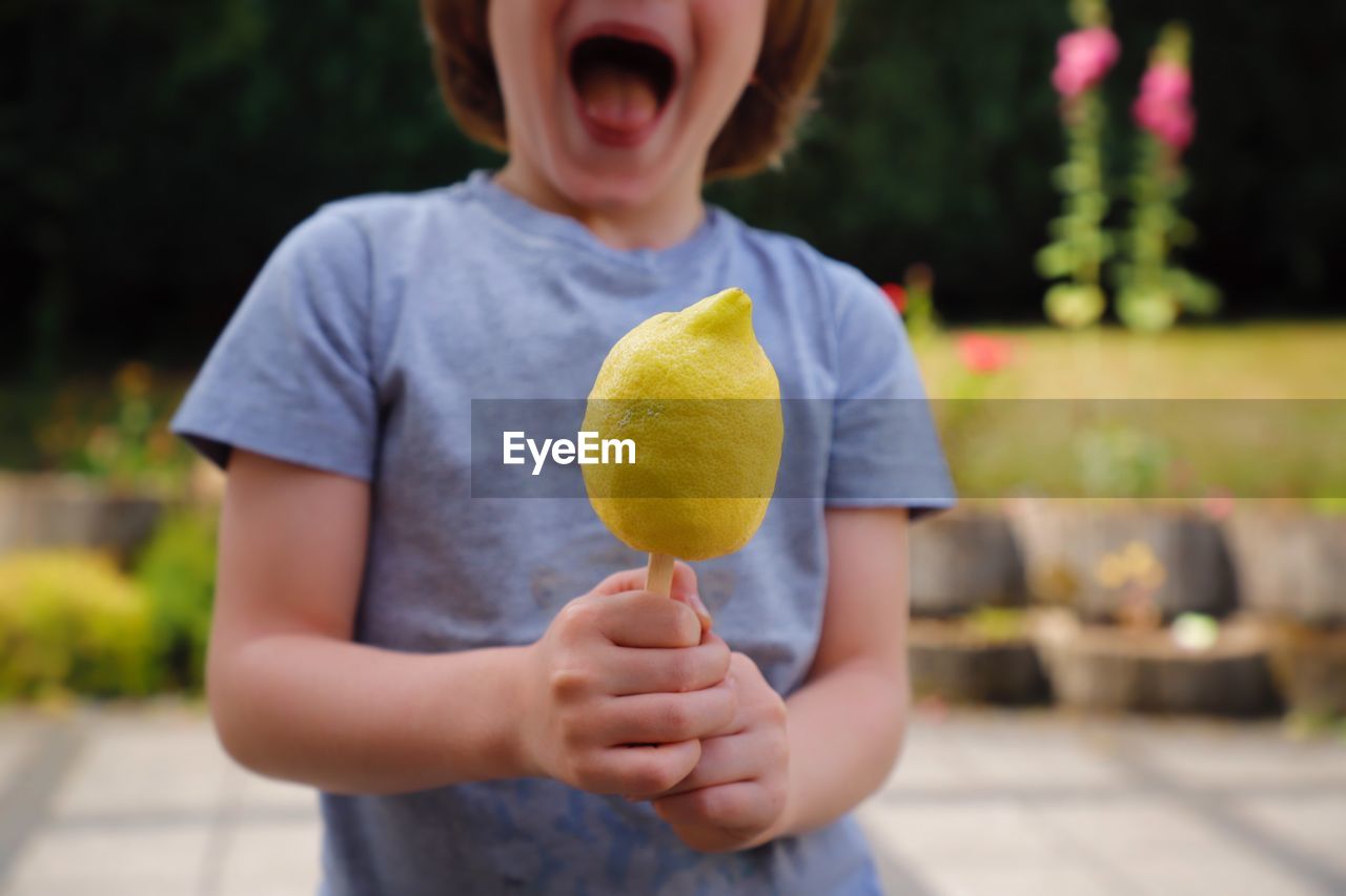 Midsection of boy holding lemon